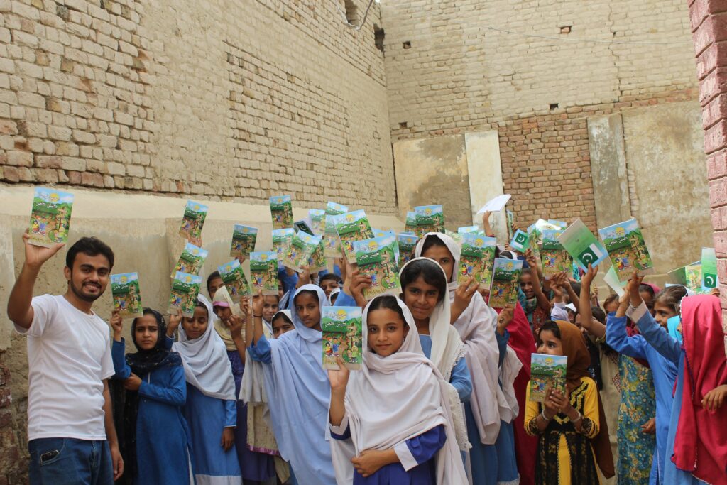large group of Pakistan kids holding copies of the Way to Happiness. 