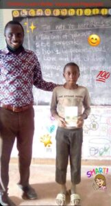 teacher standing with student holding the way to happiness book, chalk board holds way to happiness program, Happiness and Self Improvement